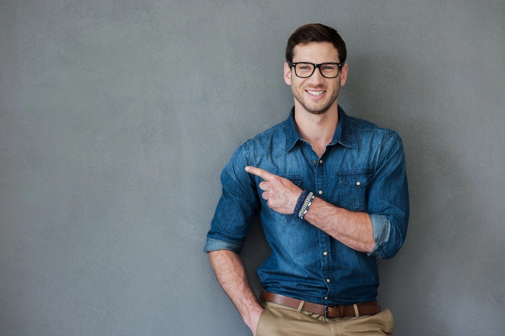 A man in blue shirt and brown pants pointing to his left.