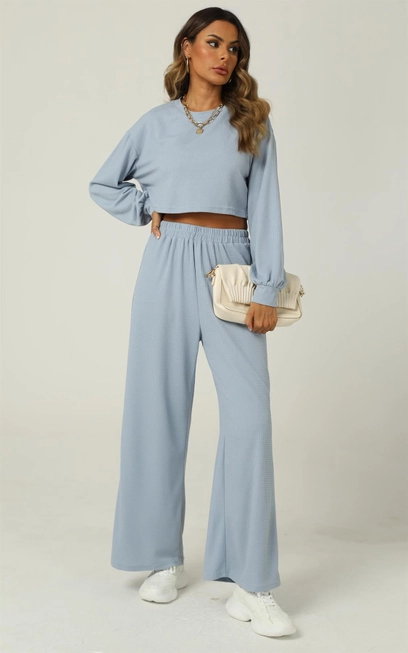 A woman wearing a blue cropped sweatshirt and matching wide-leg pants.