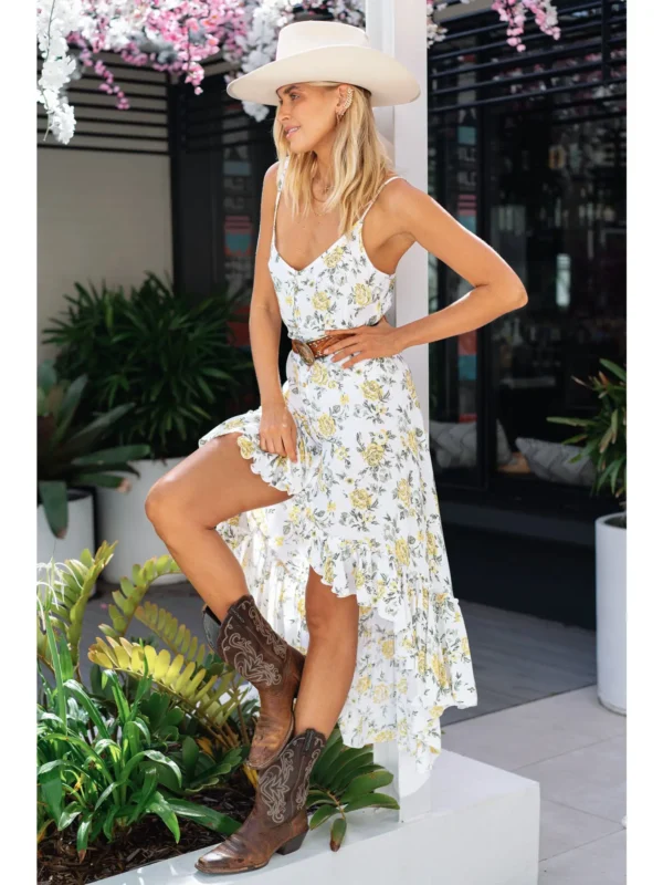 Woman wearing a white floral dress and cowboy boots.