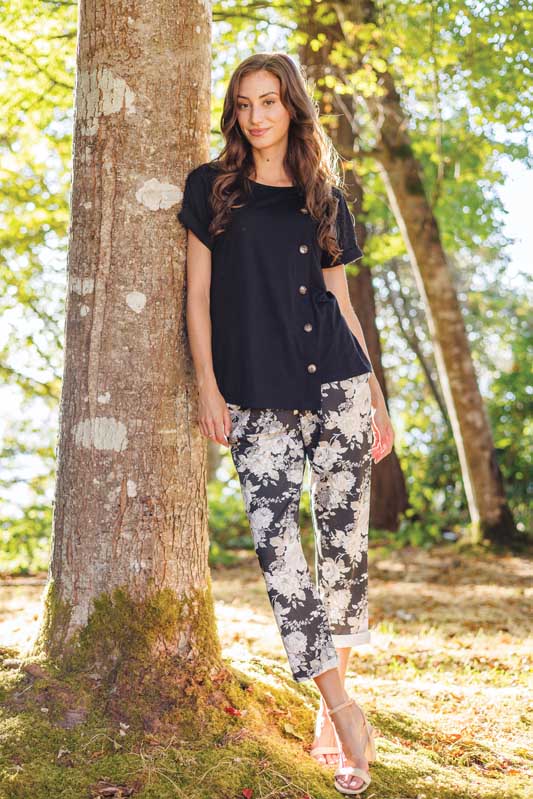 Woman wearing black top and floral pants.