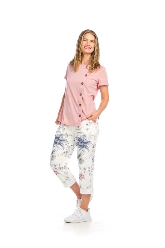 Woman wearing pink shirt and white floral pants.