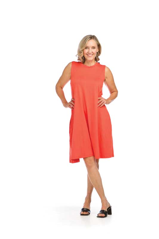 Woman in coral sleeveless dress smiling.