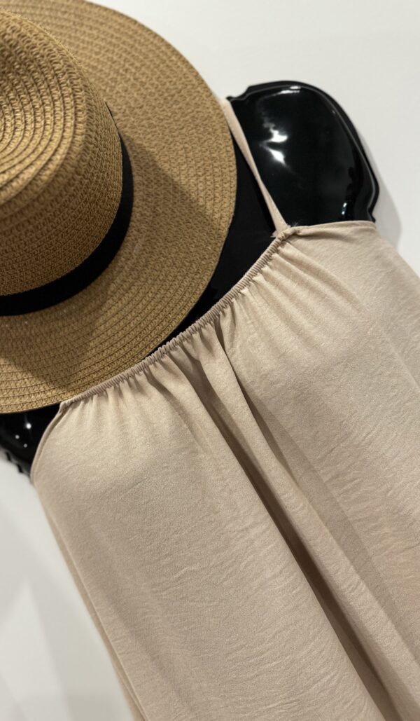 Beige sleeveless dress with straw hat.